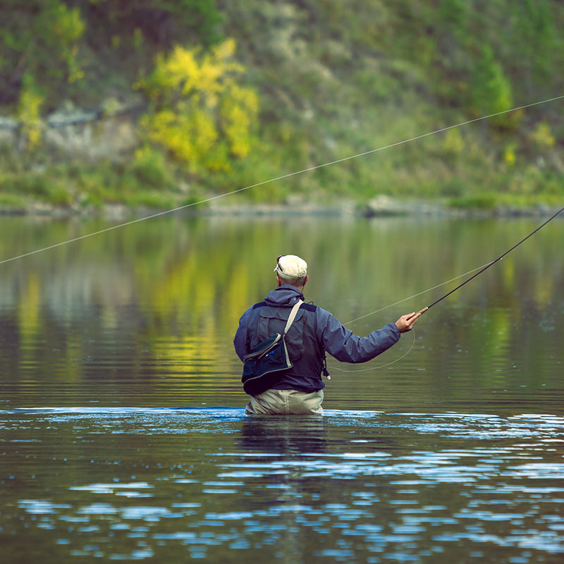 Fly fisherman wading in the deep river